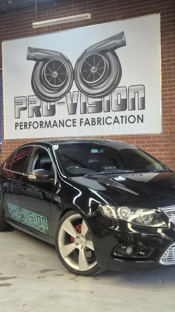 Black Pro-Vision performance sedan in front of the workshop sign