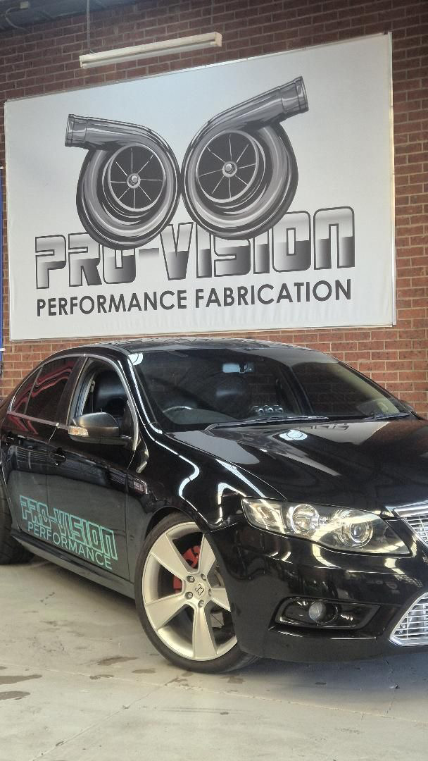 Black Pro-Vision performance car in front of the large Pro-Vision workshop sign