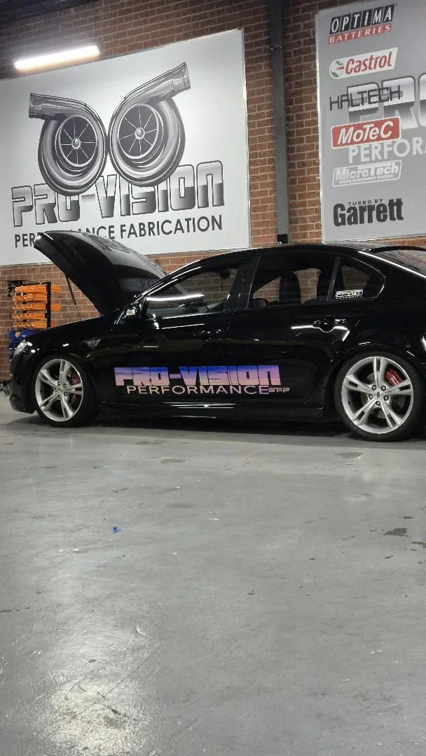 Black Pro-Vision performance sedan with bonnet open in the workshop
