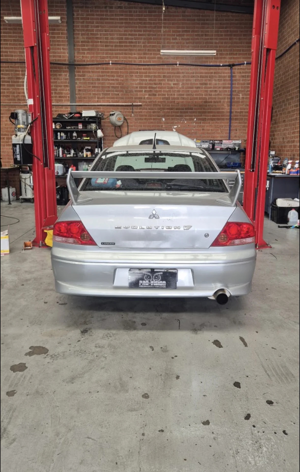 Silver Mitsubishi Evolution between workshop lift posts