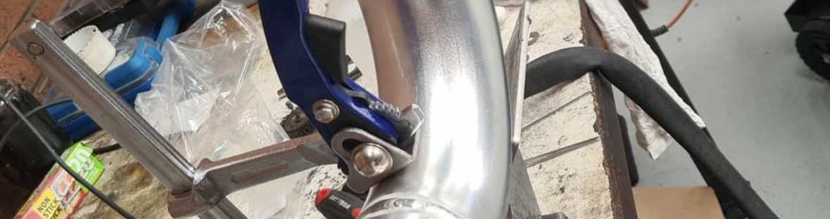 Polished alloy pipe being shaped and fitted at the workbench