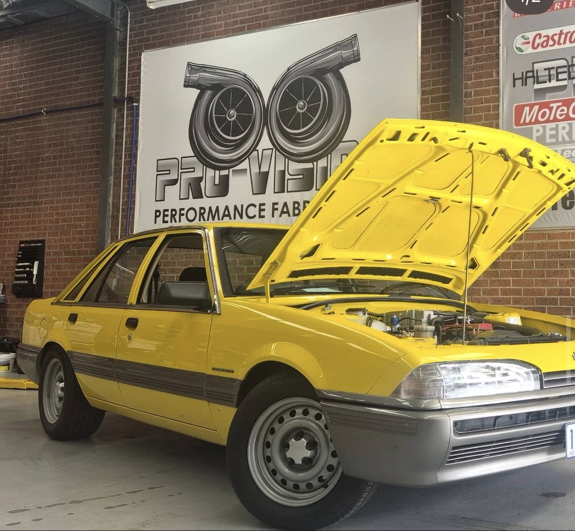 Yellow Holden VL Turbo with its bonnet open in the workshop